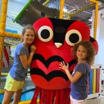 Two children hugging the friendly mascot at The Jelly Lounge soft play Windsor, creating cherished memories